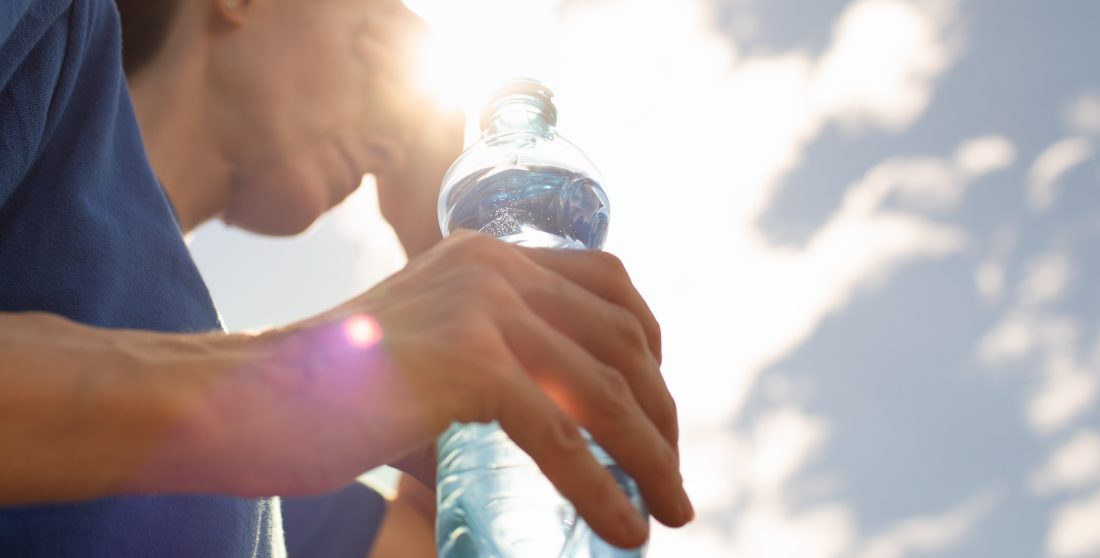 Une femme boit de l'eau pendant la canicule